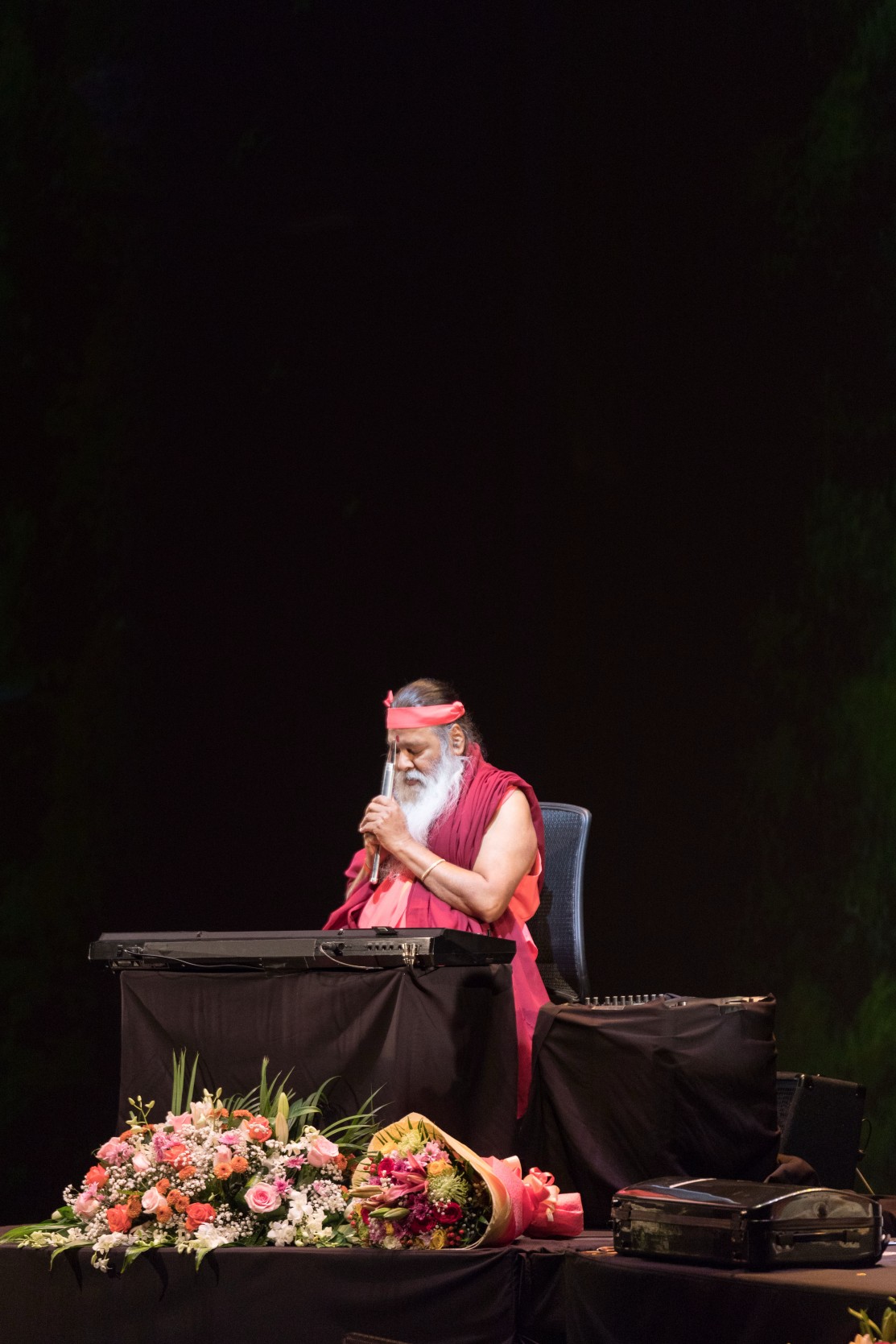Sri Swamiji playing flute on stage